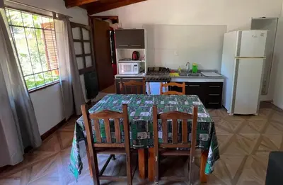 a kitchen with a table and chairs and a refrigerator at Pequeño chalet con frente al arroyo in Villa General Belgrano