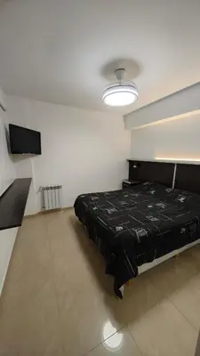 a bedroom with a black bed in a white room at Dpto amplio con piscina, Excelente ubicación in Villa Carlos Paz
