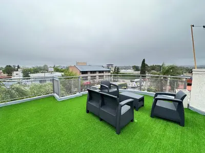a balcony with black chairs and green grass at Departamentos Sol y Lago in Villa Carlos Paz