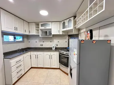 a kitchen with white cabinets and a refrigerator at Departamentos Sol y Lago in Villa Carlos Paz