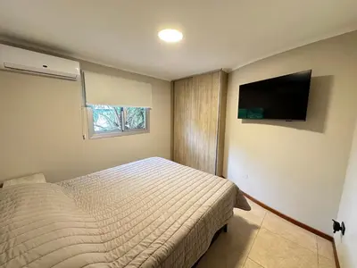a bedroom with a bed and a flat screen tv at Departamentos Sol y Lago in Villa Carlos Paz