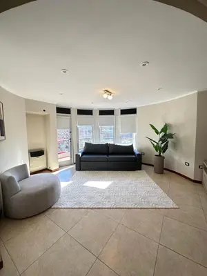 a living room with a black couch and a rug at Departamentos Sol y Lago in Villa Carlos Paz