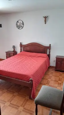 a bedroom with a bed with a red comforter and a chair at La casa del pino in Mina Clavero