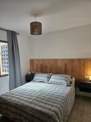 a bedroom with a bed and two tables and a lamp at Luminoso departamento in Cordoba