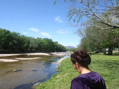 a woman is standing next to a river at Alojamiento El Pucará in San Antonio de Arredondo