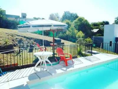 a table and two chairs and an umbrella next to a pool at Alojamiento El Pucará in San Antonio de Arredondo