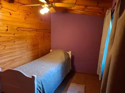 a bed in a room with a wooden wall at Orión VGB in Villa General Belgrano