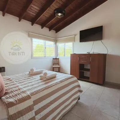 a bedroom with a bed and a flat screen tv at Tara Inti in Merlo