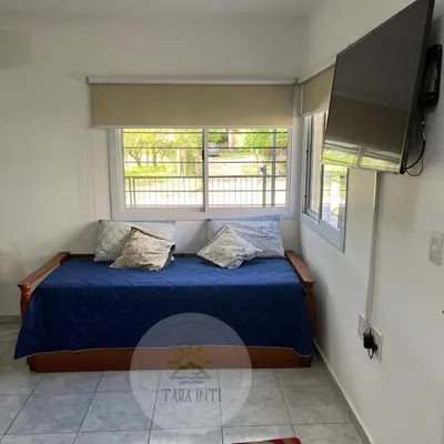 a bedroom with a bed with blue sheets and two windows at Tara Inti in Merlo