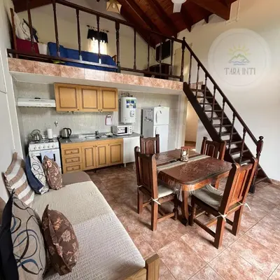 a kitchen and dining room with a table and a staircase at Tara Inti in Merlo