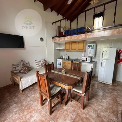a dining room with a table and a kitchen at Tara Inti in Merlo