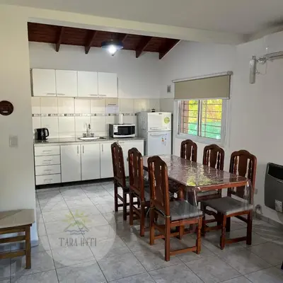 a kitchen with a table and chairs and a kitchen with white cabinets at Tara Inti in Merlo