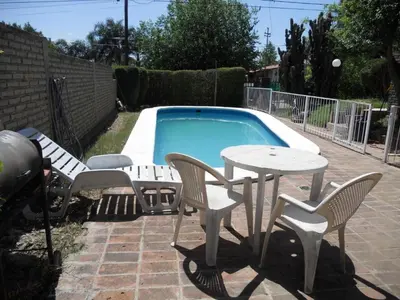 a table and chairs next to a swimming pool at Bienvenidos a la Casa de Graciela & Carlos in Villa Carlos Paz