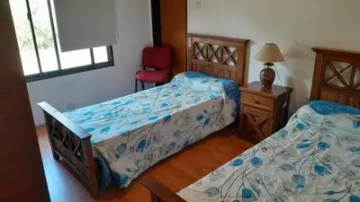 a bedroom with two beds and a red chair at Habitación doble SOLO PARA DAMAS in Villa General Belgrano