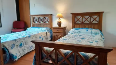 a bedroom with two beds and a table and a chair at Habitación doble SOLO PARA DAMAS in Villa General Belgrano