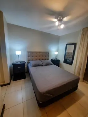 a bedroom with a bed and two night stands with lamps at Amplio Departamento en Nueva Cordoba in Cordoba
