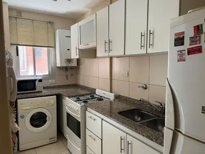 a kitchen with white cabinets and a sink and a refrigerator at Amplio Departamento en Nueva Cordoba in Cordoba