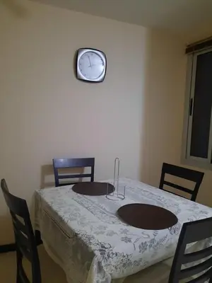 a table with two chairs and a clock on the wall at Amplio Departamento en Nueva Cordoba in Cordoba
