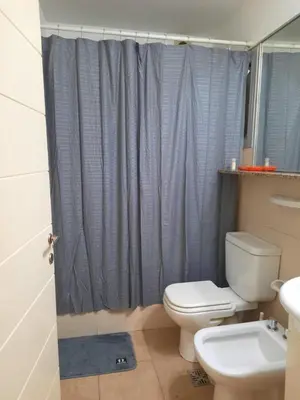 a bathroom with a toilet and a blue shower curtain at Amplio Departamento en Nueva Cordoba in Cordoba
