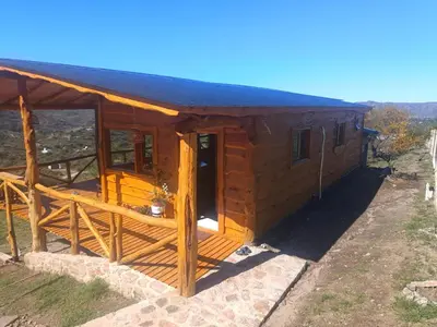a large wooden cabin with a black roof at Las Piedras in Cuesta Blanca