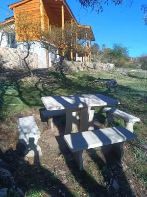 a picnic table and benches in front of a cabin at Las Piedras in Cuesta Blanca
