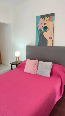 a pink bed with a painting of a woman at Habitación con baño zona cucú 2 personas in Villa Carlos Paz