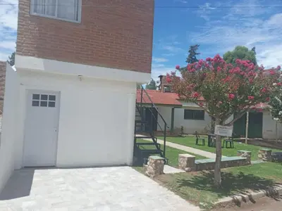 a white garage with a tree in front of a building at Bonita in Villa Cura Brochero