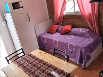 a small bedroom with a purple bed and a table at Bonita in Villa Cura Brochero