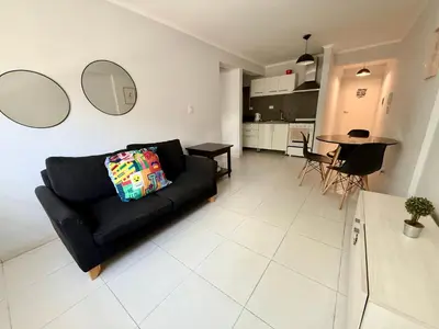 a living room with a black couch and a kitchen at Departamento para dos personas VILLA SOL in Cordoba