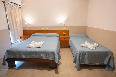 two beds in a room with towels on them at Hosteria Cruz del Sur in Villa Carlos Paz