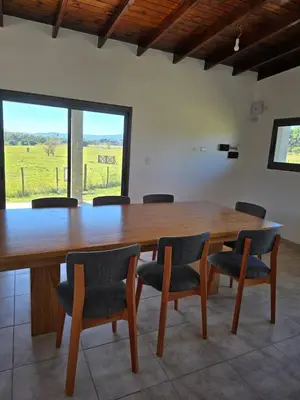 a large wooden table with chairs and a large window at Casa Los Reartes in Villa General Belgrano