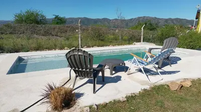 two chairs sitting next to a swimming pool at Posta de Los Geranios in Villa Parque Siquiman