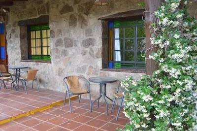 a patio with chairs and a table and windows at Rumi Huasi Cabañas in Mina Clavero