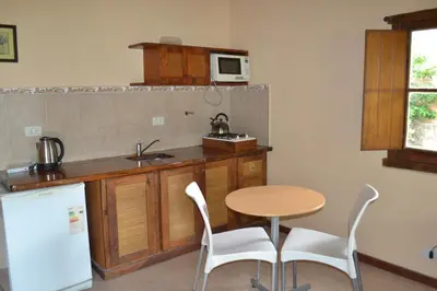 a kitchen with a table and a sink and a microwave at Rumi Huasi Cabañas in Mina Clavero