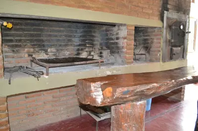 a brick fireplace with a table in front of it at Rumi Huasi Cabañas in Mina Clavero