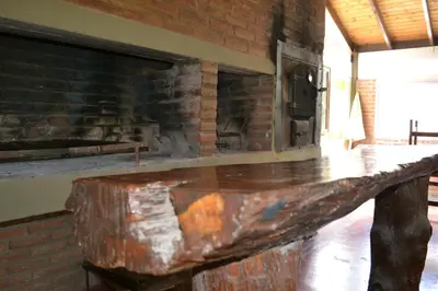 a wooden table in front of a brick fireplace at Rumi Huasi Cabañas in Mina Clavero