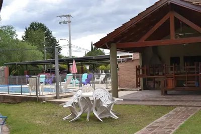 two white chairs sitting on top of a table near a pool at Rumi Huasi Cabañas in Mina Clavero