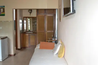 a bedroom with a bed with an orange pillow on it at Rumi Huasi Cabañas in Mina Clavero