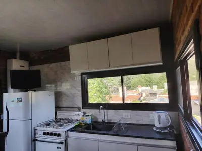 a kitchen with a sink and a refrigerator and a window at Panorámica Sierras in Villa Carlos Paz