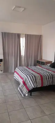 a bedroom with a bed with a striped blanket on it at calido descanso in Rio Cuarto