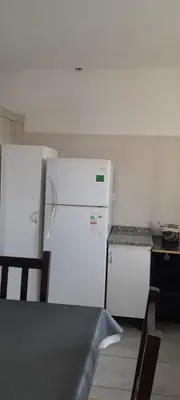 a kitchen with a white refrigerator and a table at calido descanso in Rio Cuarto