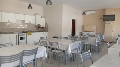 a dining room with tables and chairs and a kitchen at Apartamento villa Carlos Paz in Villa Carlos Paz