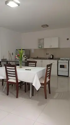 a kitchen with a white table with chairs and a table and a kitchen at Apartamento villa Carlos Paz in Villa Carlos Paz