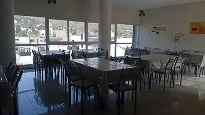a dining room with tables and chairs and windows at Apartamento villa Carlos Paz in Villa Carlos Paz