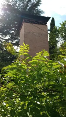 a brick tower behind a tree with green leaves at Abedules VGB in Villa General Belgrano