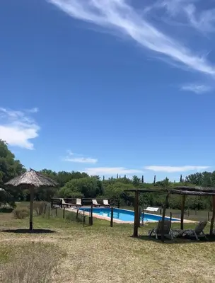 a pool with chairs and umbrellas next to at Reserva Ichacuna in Los Hornillos