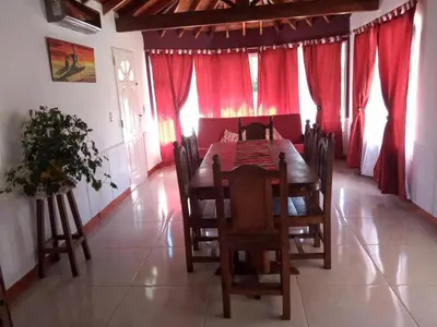 a dining room with a wooden table and red curtains at Divina Providencia in Merlo