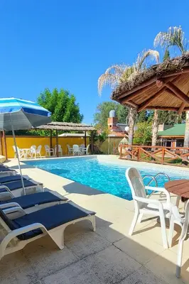 a swimming pool with chairs and a table and an umbrella at Complejo Pueblo Bonito Mayu Sumaj in San Antonio de Arredondo