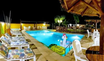 a pool at night with white chairs and a girl in the water at Complejo Pueblo Bonito Mayu Sumaj in San Antonio de Arredondo