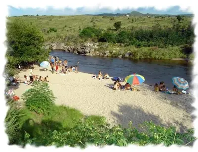a group of people sitting on a beach near a river at Complejo Pueblo Bonito Mayu Sumaj in San Antonio de Arredondo